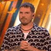 a man with a beard wearing a necklace and a shirt with a pattern on it .