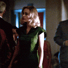 a woman in a green dress is standing in a dark room