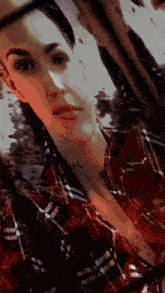 a woman wearing a plaid shirt has a tattoo on her neck