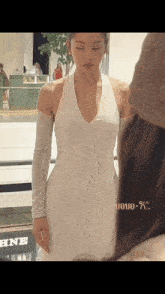 a woman in a white dress is standing in front of a hine sign