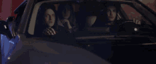 a man and two women are sitting in a car