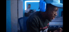 a man wearing headphones and a hat is playing a video game on his phone .