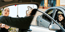 a woman is standing next to a man in a car while a man is sitting in the car .