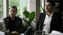 a man and a woman are sitting at a desk with a netflix logo on the bottom