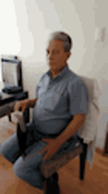 a man is sitting in a chair in a living room with his hands on his hips .