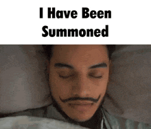 a man with a mustache is laying in bed with his eyes closed and the words i have been summoned above his head .