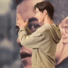 a man in a hoodie is standing in front of a large painting of a man .