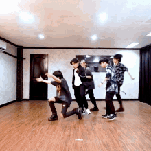 a group of young men are dancing in a room with wood floors