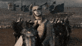 a man riding a horse with a cross on his chest stands in front of a crowd of soldiers