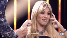 a woman with blonde hair and a necklace is being touched by a man in a floral shirt
