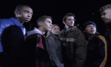 a group of young people are standing next to each other in a dark room and looking at something .
