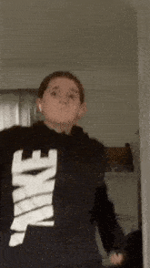 a girl wearing a black nike hoodie is standing in a doorway .