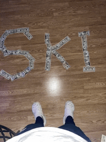 a person standing on a wooden floor with the word ski spelled out in dollar bills