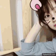 a girl with a cross tattoo on her wrist is wearing a mouse ear mask .