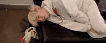 a man in a white shirt is laying on a black couch .