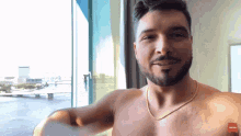a shirtless man with a gold chain around his neck is smiling and looking at the camera