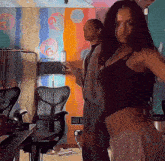 a woman in a black top is dancing in a room with a colorful wall