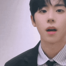 a close up of a man wearing a suit and tie with a surprised look on his face