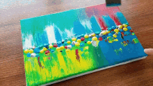 a painting on a wooden table with a person holding a brush