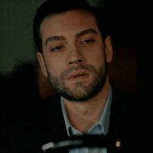 a man with a beard and a blue shirt is looking at something