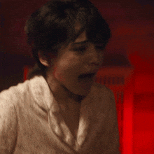 a close up of a person 's face with a red light in the background