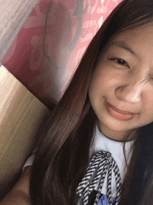 a girl with long brown hair is smiling and looking at the camera