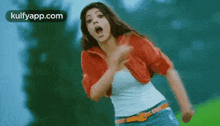 a woman in a red jacket and jeans is running in a field .
