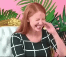 a woman with red hair is laughing and covering her nose with her hand .