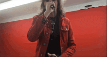 a person wearing a red jacket is singing into a microphone