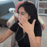 a woman sitting in a pink and white chair covering her mouth