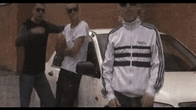 a group of young men are standing next to a car .