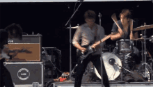 a man playing a guitar on stage in front of a vox amplifier