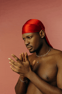 a shirtless man with a red headband and pearl necklace