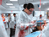 a woman in a bloody surgical gown holds a needle