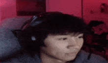 a man wearing headphones and a microphone is sitting in front of a computer screen .