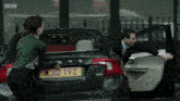 a man and a woman are getting out of a car with a license plate that says aj12 tvz