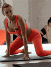 a woman in orange leggings is kneeling on a mat