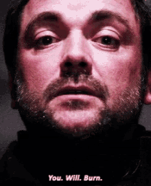 a close up of a man 's face with the words " you will burn " on the bottom