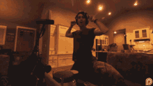 a man wearing headphones and a red shirt is playing drums in a living room