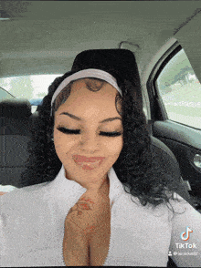 a woman with curly hair is sitting in a car with a tiktok post