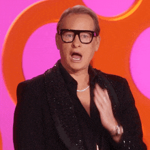 a man wearing glasses and a tuxedo has his mouth open