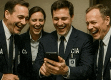 a group of cia agents are laughing and looking at a phone