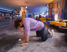 a man in a purple sweater is doing push ups on the floor in a room with tires .