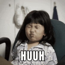 a little girl is making a funny face with the word huuh written on her face