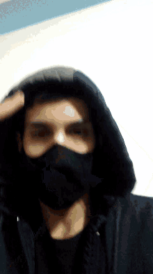 a person wearing a hooded jacket and a black mask on their face