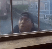 a man is looking out of a window at a house .