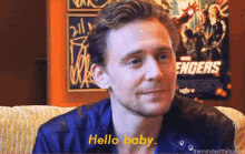 a man sitting on a couch with a poster of the avengers behind him