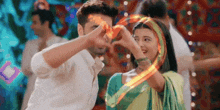 a man and a woman are making a heart shape with their hands while dancing .