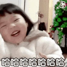 a little girl is laughing in front of a christmas tree while wearing a white jacket .