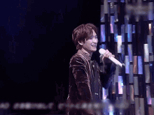 a man singing into a microphone in front of a wall that says ' aa ' on it